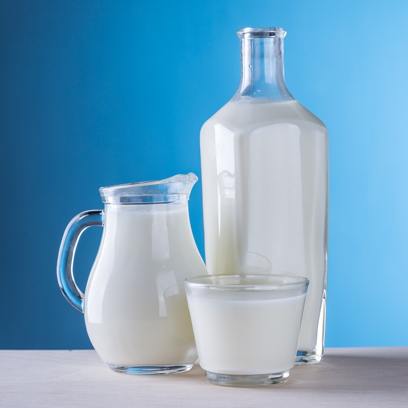 A glass pitcher, jug and glass containing milk.