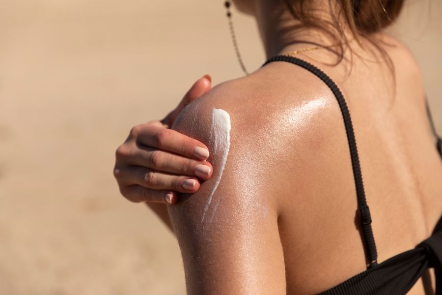 woman applies sun block to shoulder