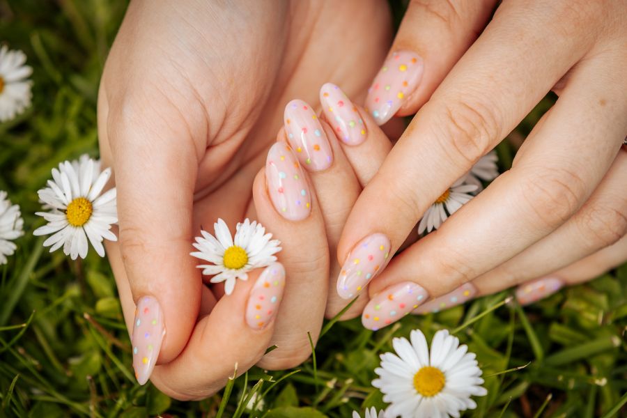 pastel nails surrounded by daisies in grass