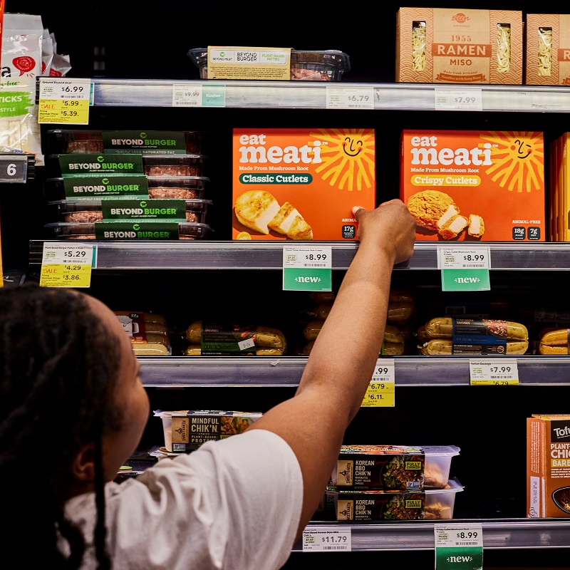 Woman picking up packaged food in supermarket.