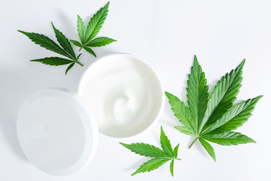 Cannibis leaves next to open moisturizer container