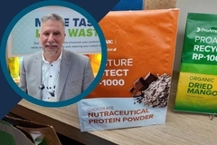 ProAmpac video thumbnail: Man standing beside sustainable product packaging displays, including chocolate nutraceutical protein powder and dried mang ProAmpac video thumbnail: Man standing beside sustainable product packaging displays, including chocolate nutraceutical protein powder and dried mang