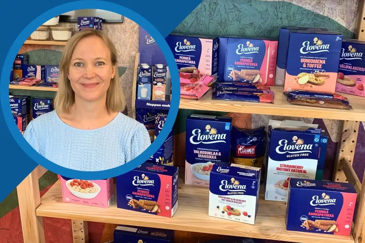 Raisio video thumbnail: Smiling woman in front of wooden shelves displaying Elovena oatmeal, snack biscuits, and other packaged food products